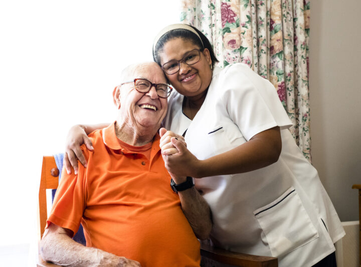 Portrait of a smiling senior man and nurse embracing