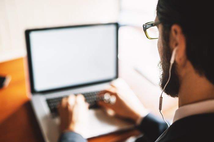 man with headphone looking at a laptop